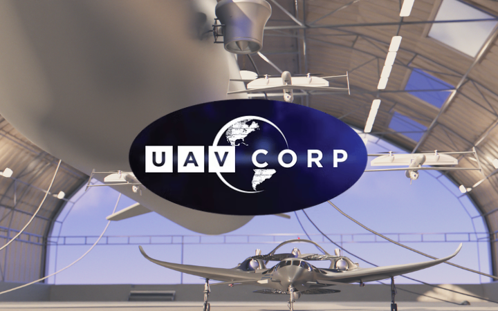 UAV Corp logo on a blue oval sign in a hangar, with small unmanned aircraft on a stand beneath.